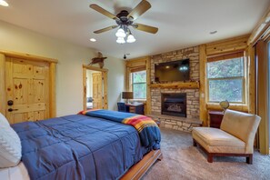 A bedroom with a bed, a chair, a fireplace, a television, and a ceiling fan. - 7 Min to Slopes! 3BD 2.5BA 5 Beds + Sofa Bed Cabin (Big Bear)