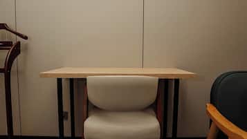 Una habitación con una mesa de madera, una silla con asiento acolchado y una alfombra azul estampada.