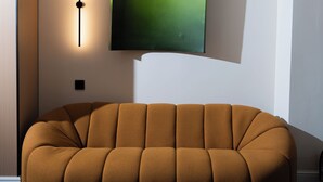A modern living room with a sofa, a wall-mounted television, and recessed lighting. - Nooma Hotel on Frunze (Bishkek)