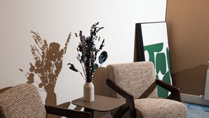 A room with two upholstered chairs, a small table, and a vase with dried plants. - Nooma Hotel on Frunze (Bishkek)