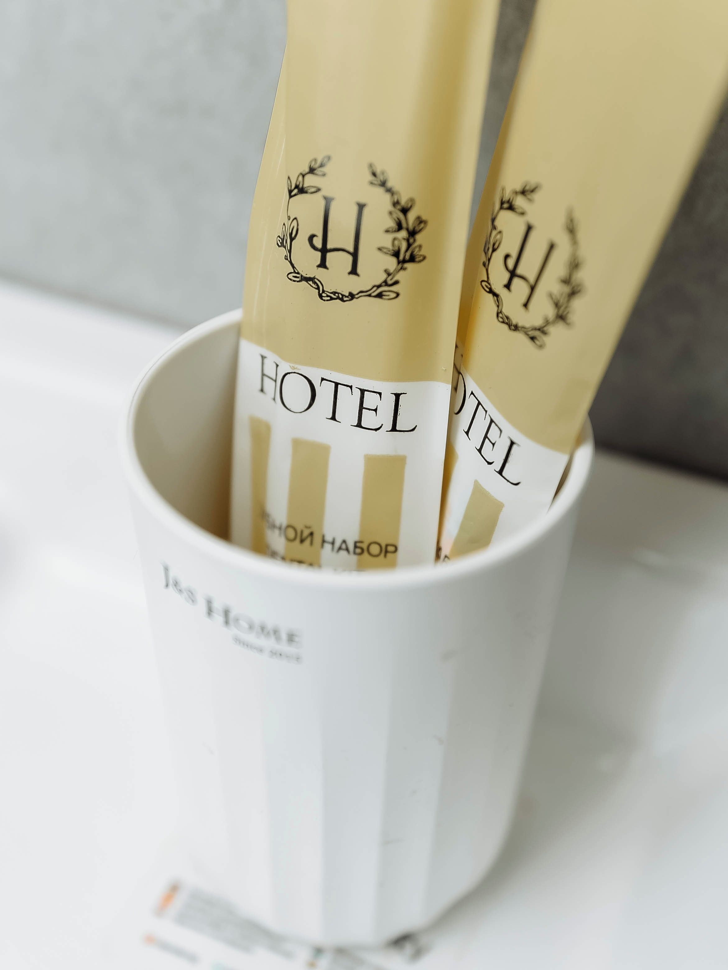A white cup with vertical stripes containing two hotel name tags.