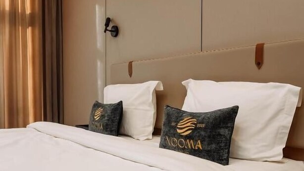A hotel room with a bed, a nightstand, and a wooden headboard. - Nooma Hotel on Frunze (Bishkek)
