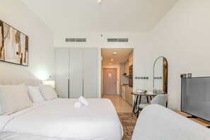 Ein Hotelzimmer mit einem großen Bett, einem Fernseher, einem Schreibtisch und einer Küchenzeile.