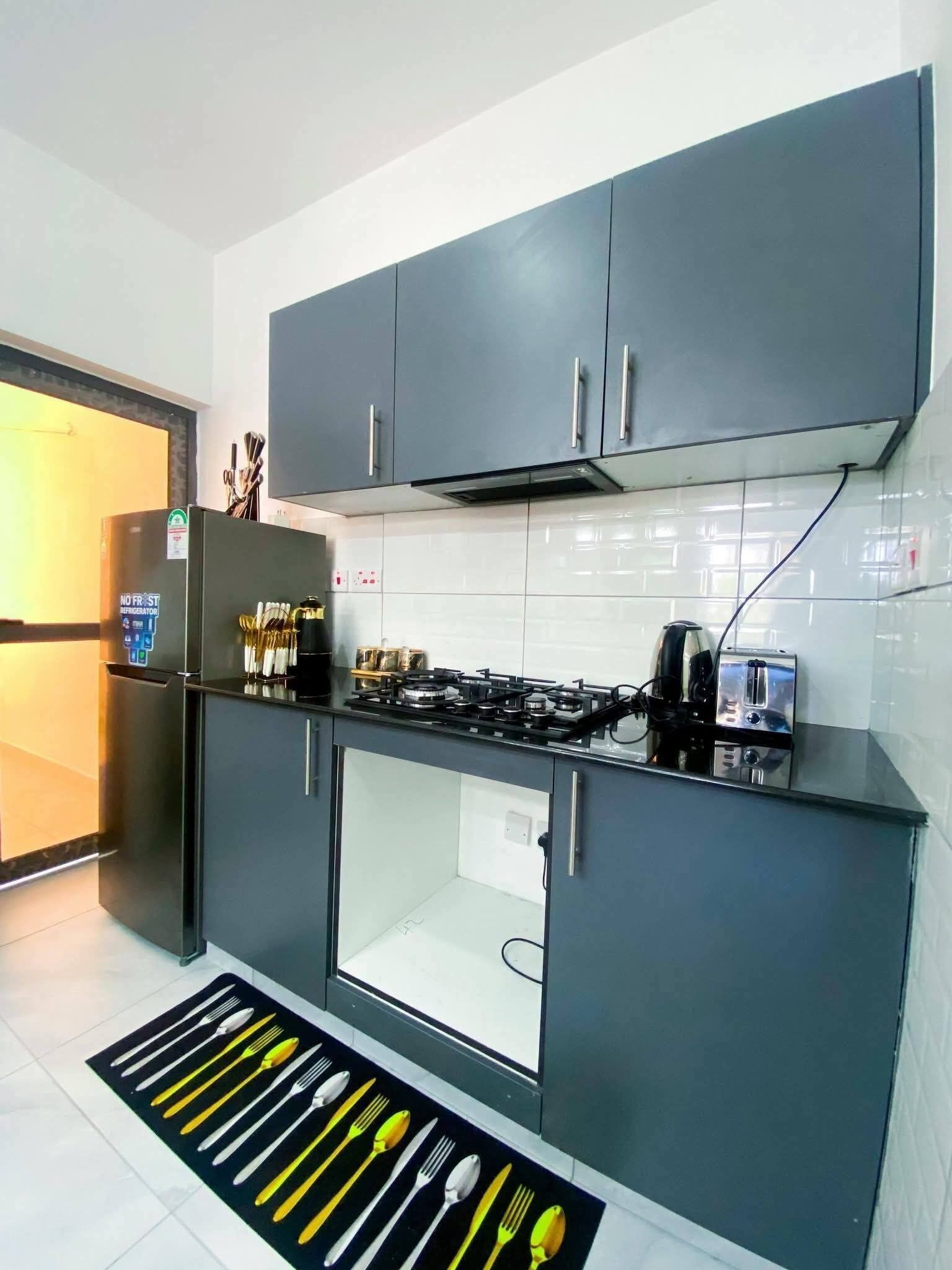 Una cocina moderna con gabinetes grises, una estufa empotrada y un refrigerador.