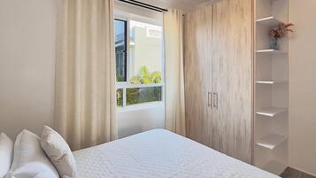 Un dormitorio con cama, cortinas, una ventana y un armario.