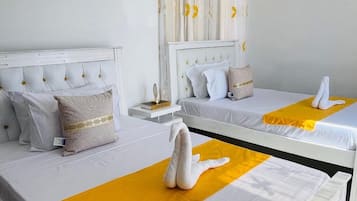 Een hotelkamer met twee bedden, elk voorzien van witte beddengoed en een geel accent.