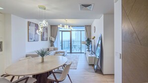 A modern dining area with a round table, chairs, and a vase of greenery. - Palace Residences - Dubai Creek Harbour (Dubai)