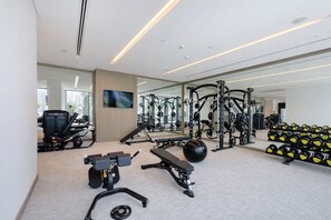 Ein modernes Fitnessstudio mit verschiedenen Trainingsgeräten, einem großen Spiegel und einer Bank.