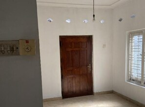 Une pièce avec une porte en bois, une fenêtre grillagée et un éclairage encastré.