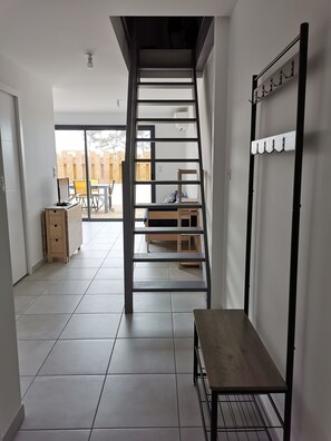 A modern interior with a staircase, a wooden bench, and a wall-mounted rack. - Cozy apartment for 5 people, 500 meters from the beach and 350 meters from downtown (Biscarrosse)
