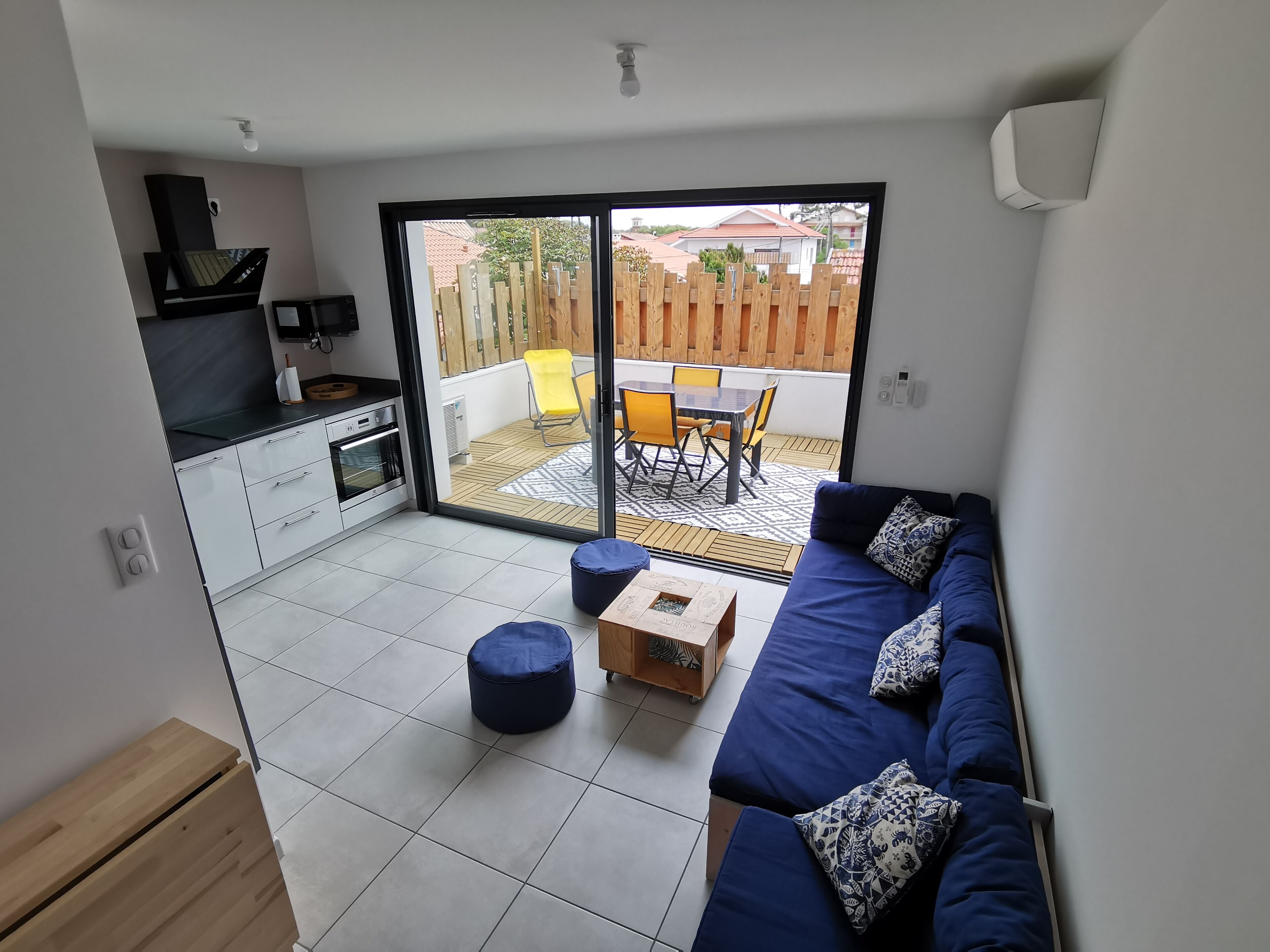 A modern living space with a kitchen, dining area, and a large sliding glass door leading to a patio.