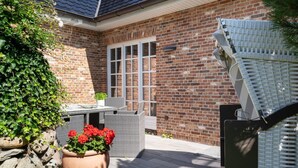 A brick house with a patio, outdoor furniture, and potted plants. - Eidumweg Apartment 2 - Modern vacation rental with a terrace, sauna, and amenities for 3 (Sylt)