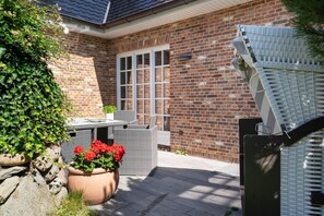 A brick house with a patio, outdoor furniture, and potted plants. - Eidumweg Apartment 2 - Modern vacation rental with a terrace, sauna, and amenities for 3 (Sylt)