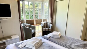 A hotel room with two beds, a television, a sofa, and a view of the outdoors. - Eidumweg Apartment 2 - Modern vacation rental with a terrace, sauna, and amenities for 3 (Sylt)