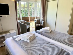 A hotel room with two beds, a television, a sofa, and a view of the outdoors. - Eidumweg Apartment 2 - Modern vacation rental with a terrace, sauna, and amenities for 3 (Sylt)