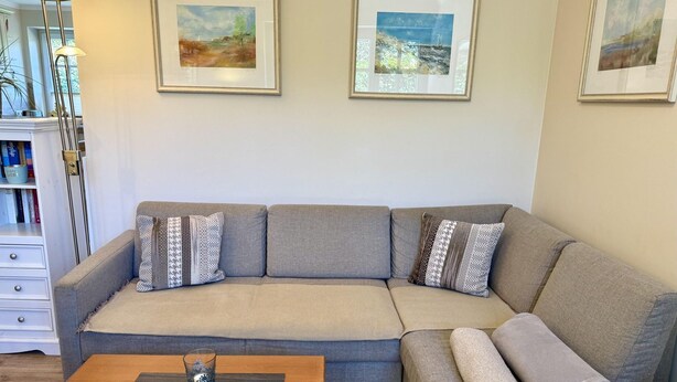 A living room with a sofa, a coffee table, and three framed artworks on the wall. - Eidumweg Apartment 2 - Modern vacation rental with a terrace, sauna, and amenities for 3 (Sylt)