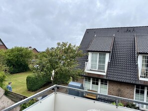 A residential building with a sloped roof, a balcony, and a view of a garden. - Kampstraße, Apartment 4a - Cozy 3-room vacation apartment with 2 balconies in a quiet (Sylt)