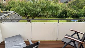 A balcony with a metal railing, a chair, and a table. - Kampstraße, Apartment 4a - Cozy 3-room vacation apartment with 2 balconies in a quiet (Sylt)