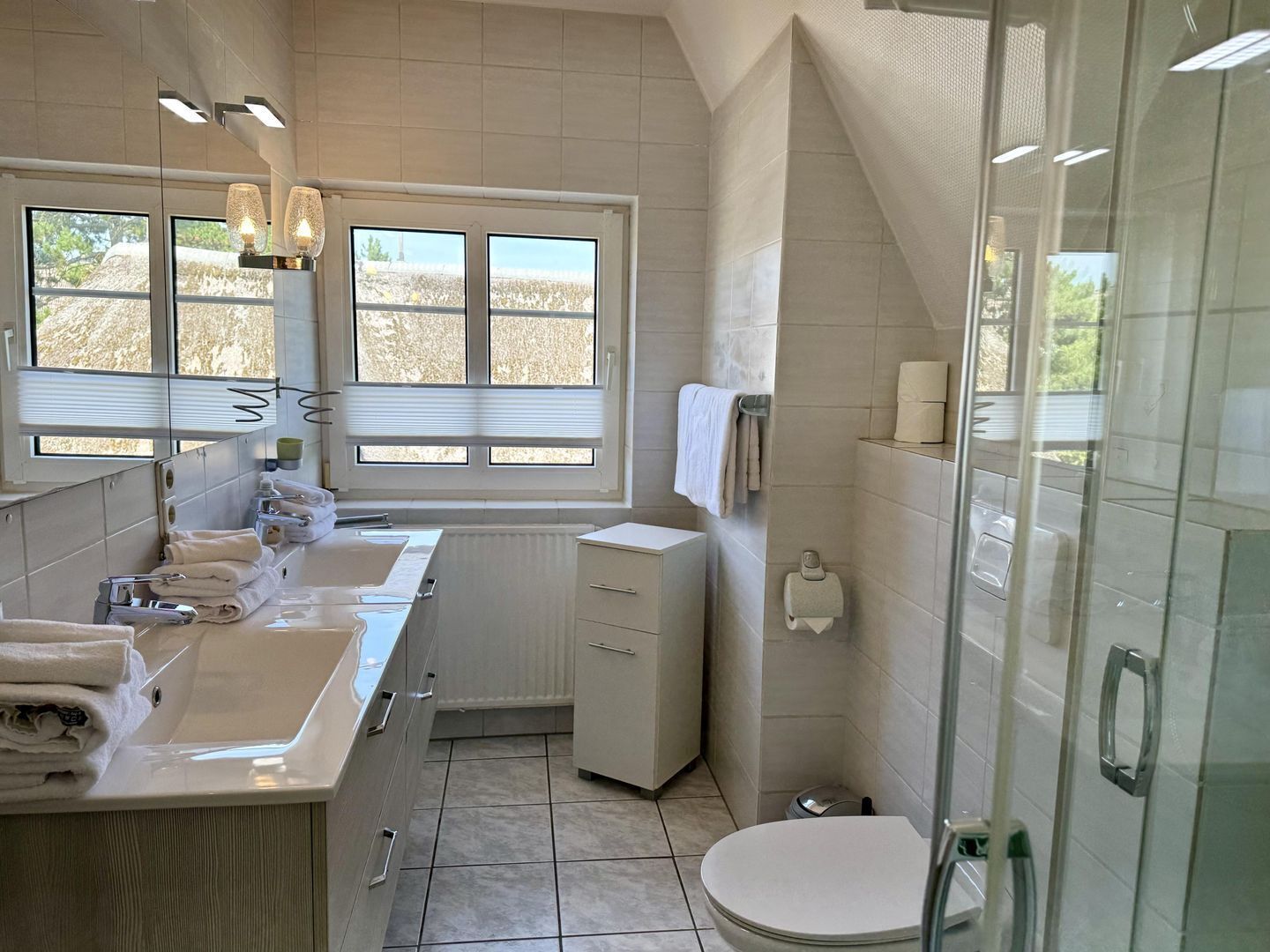 A modern bathroom with dual sinks, a toilet, and a shower area.