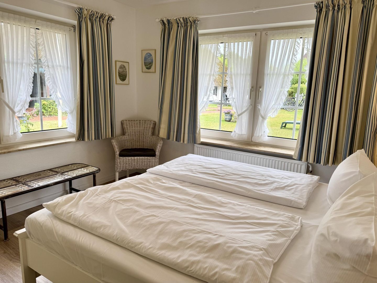 A bedroom with a bed, a chair, and a window with curtains.