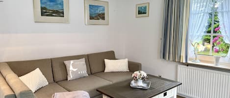 Una sala de estar con sofá, mesa de centro y ventana con cortinas.