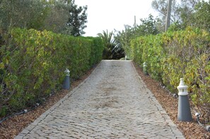 A cobblestone pathway flanked by neatly trimmed hedges and a lamp post. - Charming villa with 3 bedrooms and sea view (Santa Bárbara de Nexe)