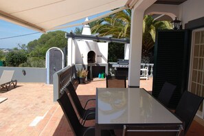Eine Terrasse im Freien mit Tisch, Stühlen, Grill und Pizzaofen.