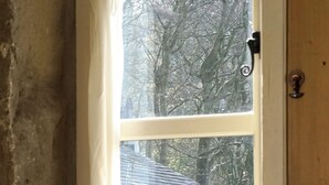 A window with a view of a brick building and trees. - Triangle Cottage - A beautifully restored and furnished luxury cottage for two (Hebden Bridge)