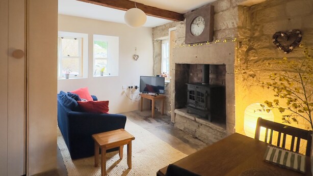 A living room with a sofa, a wooden table, a fireplace, and a television. - Triangle Cottage - A beautifully restored and furnished luxury cottage for two (Hebden Bridge)