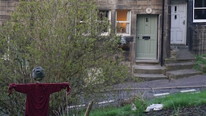 A stone building with a traditional design, featuring a chimney, multiple windows, and a door with a number plaque. - Triangle Cottage - A beautifully restored and furnished luxury cottage for two (Hebden Bridge)