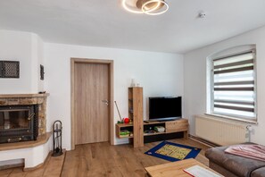 A modern living room with a fireplace, a television, and a window with blinds.