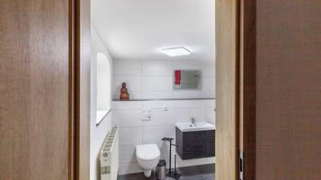 A modern bathroom with a toilet, sink, and shower.