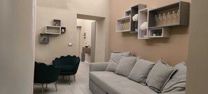 A modern living room with a grey sofa, a dark green armchair, and built-in shelves with decorative items. - Elegant downtown apartment with a hot tub and a view of Naples (Napoli)