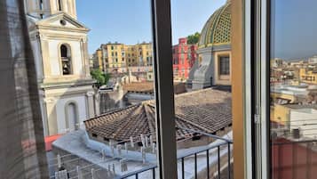 Vista di un paesaggio urbano attraverso una finestra, con un edificio che presenta una cupola e un campanile.