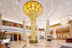A spacious lobby with a central column, multiple floors, and a modern chandelier.
