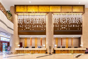 Vestíbulo de hotel con mostrador de recepción, zona de estar e iluminación decorativa.