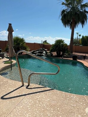 A swimming pool with a metal ladder, palm trees, and a clear sky. - 3-bedroom house in quaint Sun Lakes with luxury pool (Sun Lakes)