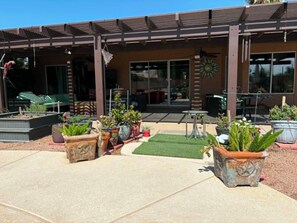 A covered patio area with outdoor seating, planters, and a building entrance. - 3-bedroom house in quaint Sun Lakes with luxury pool (Sun Lakes)