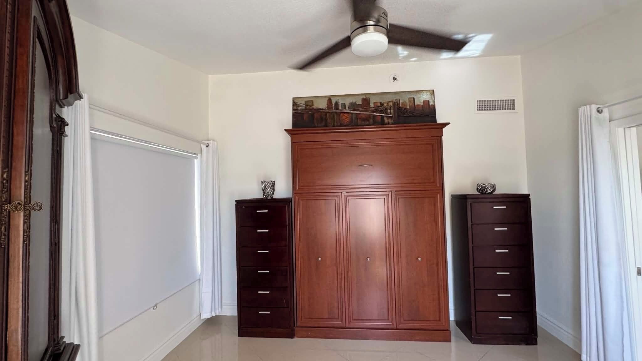 Un corridoio con un'ampia armadiatura in legno, due pensili laterali e una ventola a soffitto.