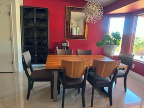 A dining area with a wooden table and chairs, a large mirror, and a potted plant. - 3-bedroom house in quaint Sun Lakes with luxury pool (Sun Lakes)