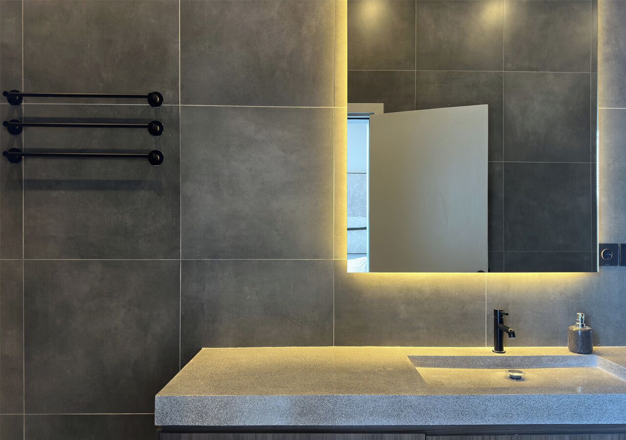 Un baño moderno con un lavamanos rectangular, un espejo y un perchero para toallas.