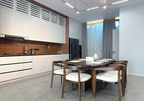 Eine moderne Küche mit weißen Schränken, einer Holzauskleidung und einem Essbereich mit einem dunklen Holztisch und Stühlen.