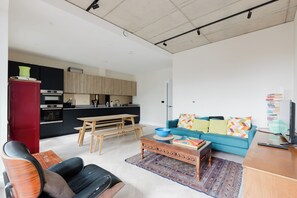 A modern living space with a kitchen, a dining area, and a seating area with a sofa and chairs. - Stylish Canal Side 2BDR Flat with Private Balcony (Greater London)