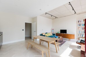 Ein geräumiges Wohnzimmer mit einer hölzernen Bank, einer Couch, einem Fernseher und einem Bücherregal.