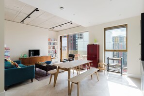 En moderne stue med en sofa, spisebord og fjernsyn. Der er reoler og et rødt skab.