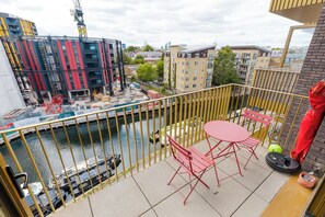 En balkon med udsigt over en flod, en byggeplads og boligbebyggelse.