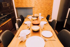 A dining table set with plates, bowls, cups, and chopsticks, surrounded by chairs. - Ninja 4BR Tennoji 5 Min (Osaka)