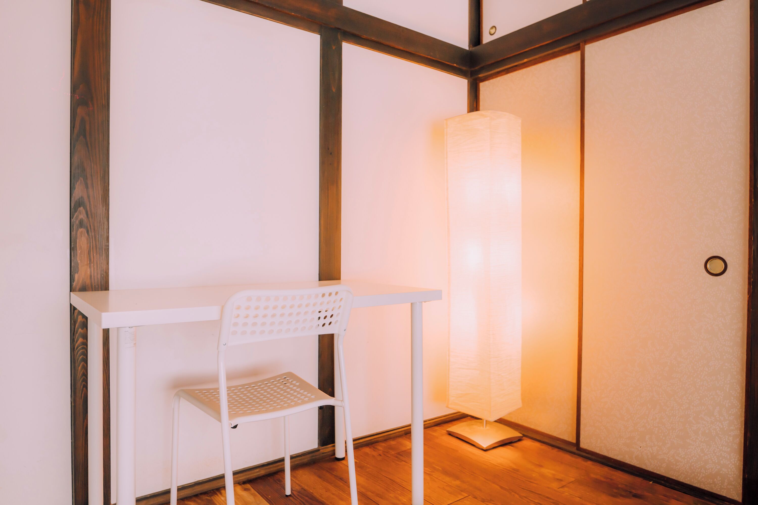 Een witte stoel en tafel in een kamer met houten vloer en een schuifdeur.