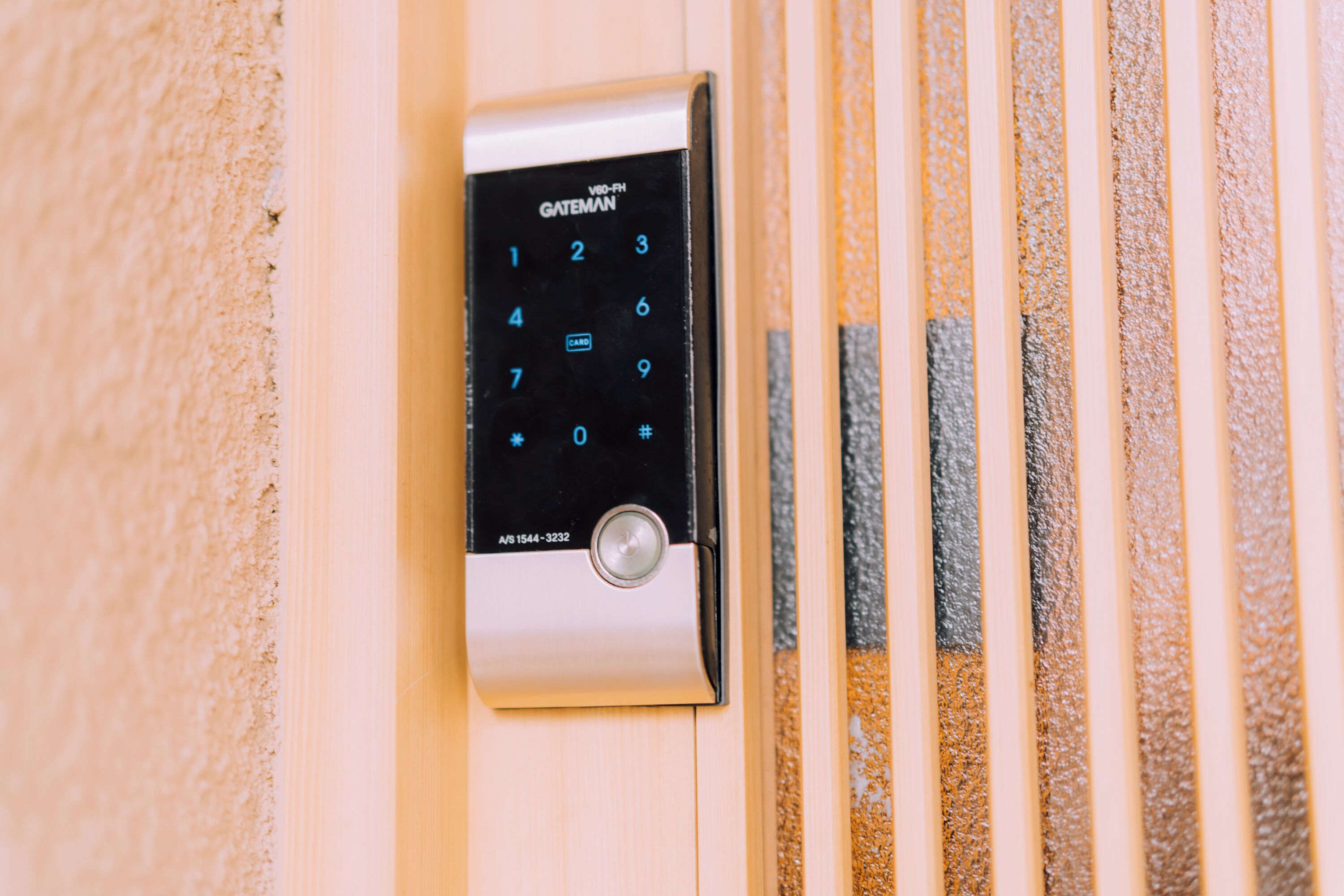 A security keypad with a numeric keypad and a card slot, mounted on a wall with vertical textured panels.