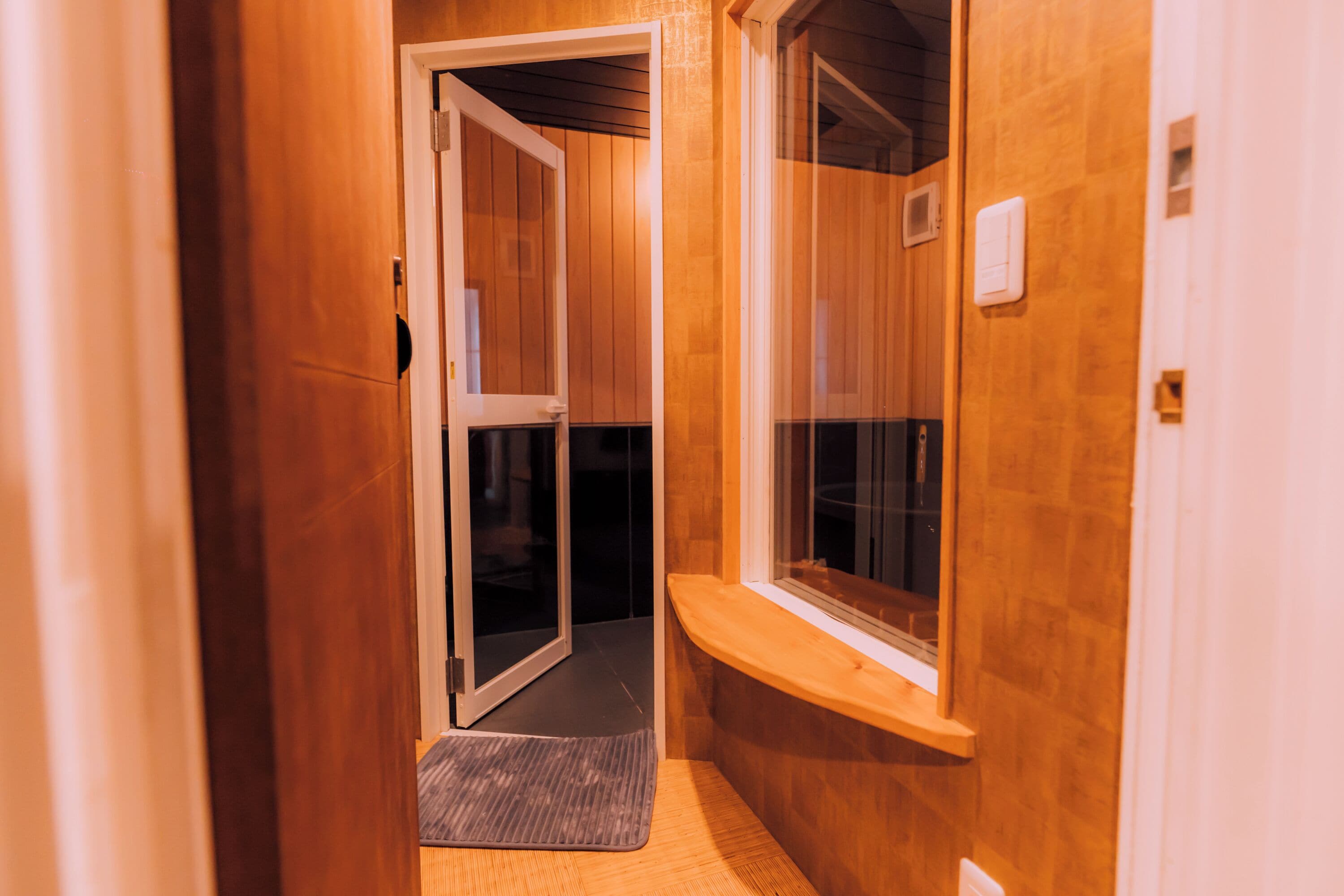 A narrow hallway with wooden walls, a glass door, and a window.